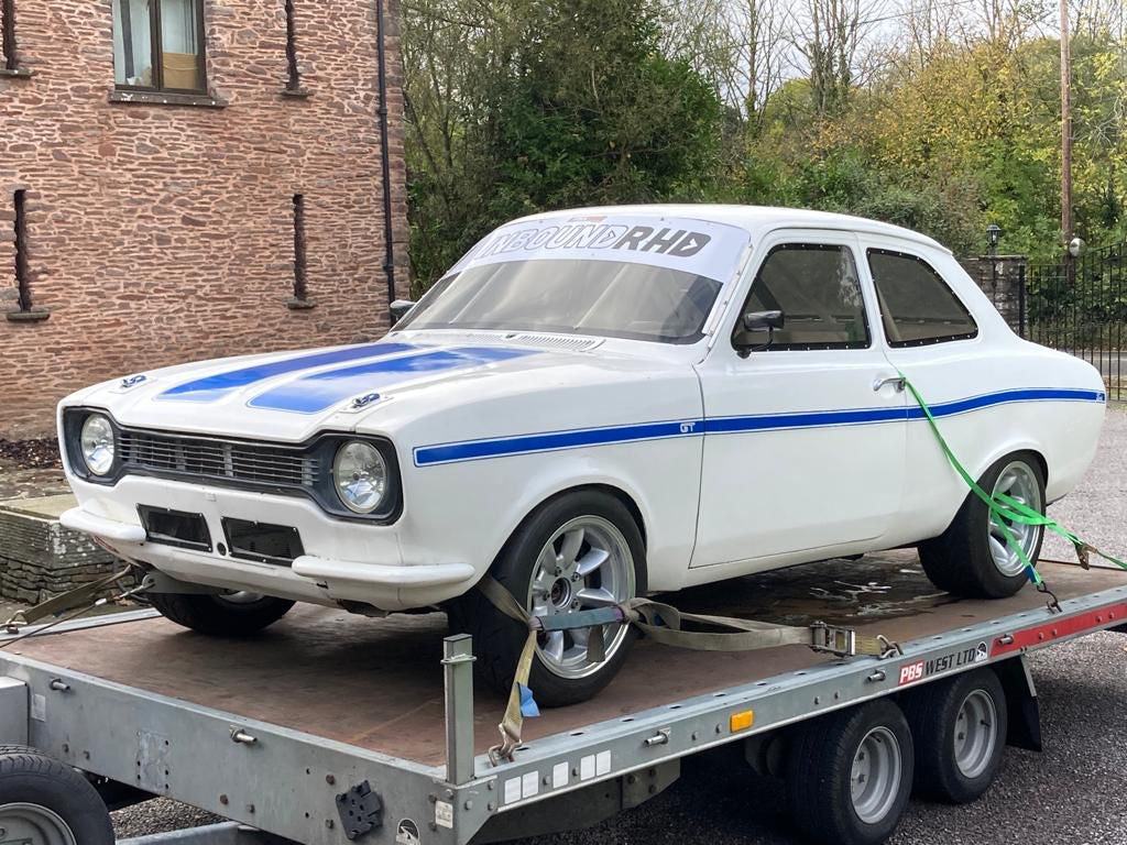 White Ford Escort secured to a vehicle transporter