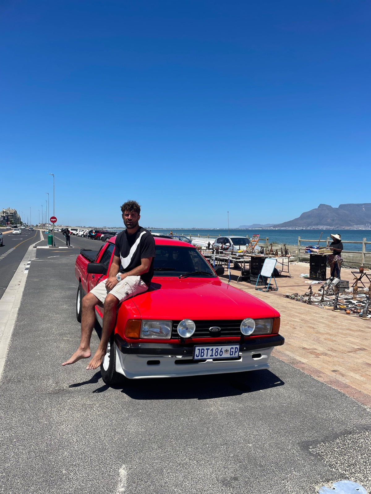Owner seated on a red Ford Bantam by the Cape Town coast