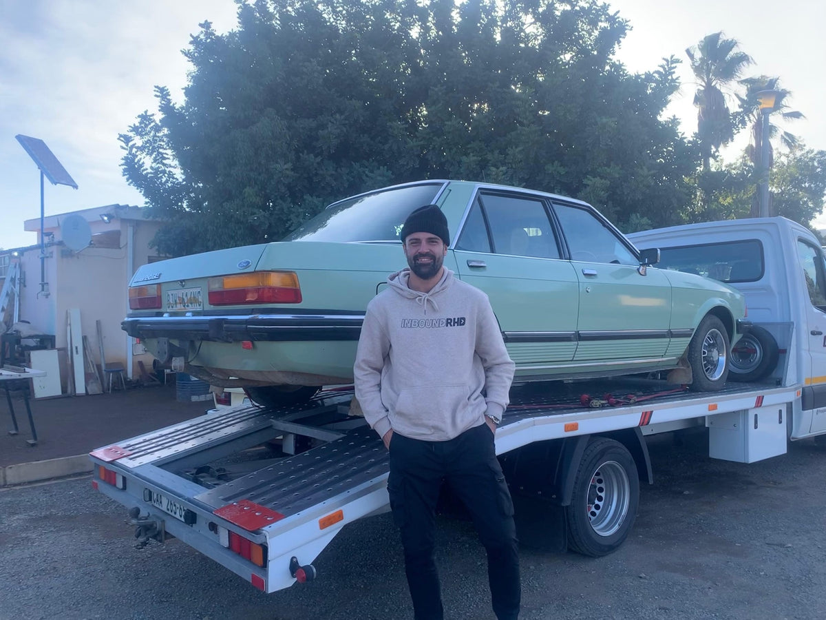 Inbound RHD specialist standing by a classic Ford on a transporter