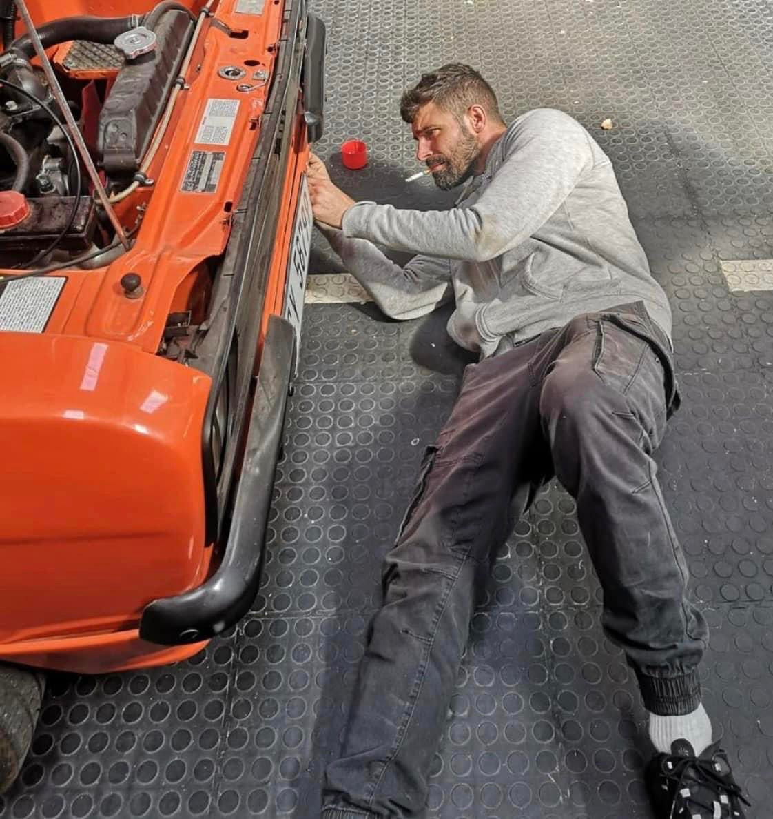 Inbound RHD mechanic working beneath a classic car